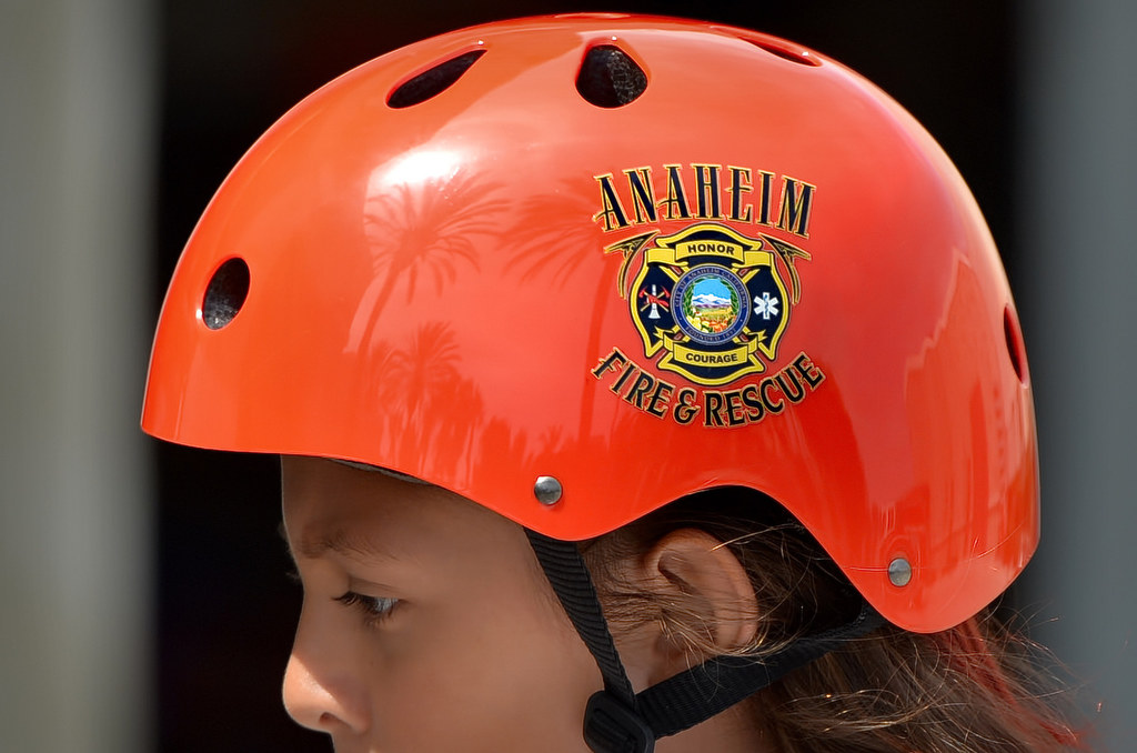 With palm trees reflected in her shiny red Anaheim Fire & Rescue helmet, 8-year-old Julia Alvarez of Anaheim bikes around Anaheim Fire & Rescue Station 3 before a press conference regarding helmet safety. Photo by Steven Georges/Behind the Badge OC