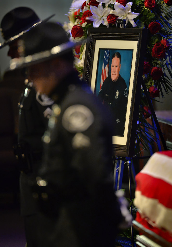 A portrait of Brea PD Officer Daniel McKinley is displayed next to his casket as officers from Brea PD Honor Guard stand watch during funeral services in Fullerton. Photo by Steven Georges/Behind the Badge OC