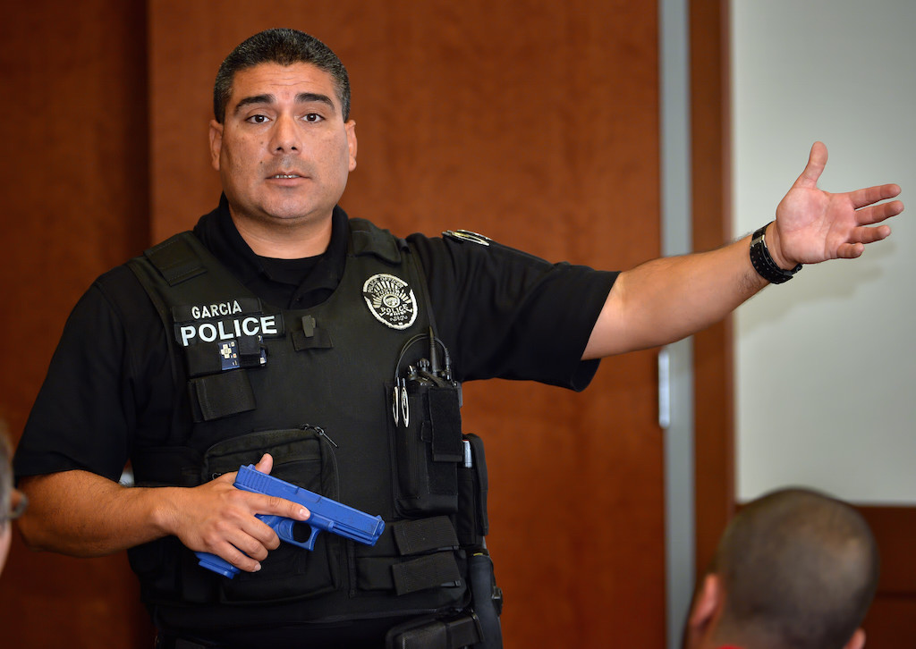 Tustin PD’s Sgt. Luis Garcia, of the gang enforcement team, holds a blue simulated gun as he talks to a group of citizens about the types of force police officers are aloud to use, when they have to use it and why it is necessary for the officers and the public’s safety.  Photo by Steven Georges/Behind the Badge OC