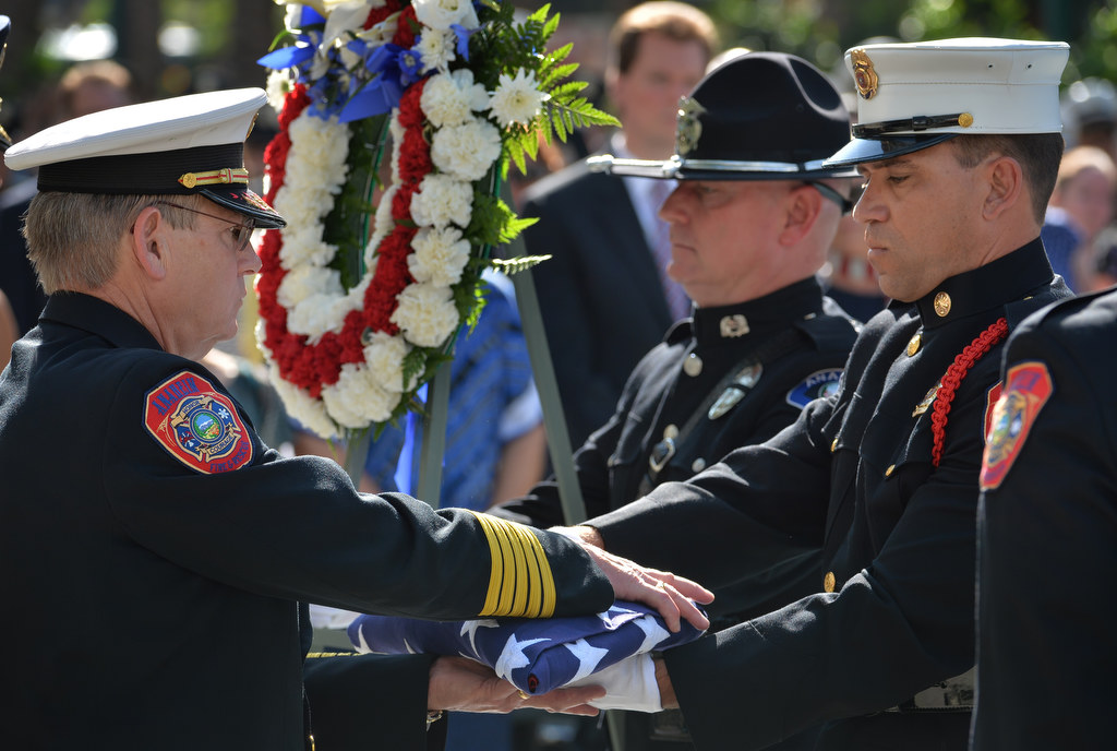 Anaheim Fire & Rescue Chief Randy Bruegman, left, receives the flag from Honor Guard Michel Bowidowicz during the 2015 9/11 Remembrance Ceremony at Anaheim Grand Plaza. Photo by Steven Georges/Behind the Badge OC