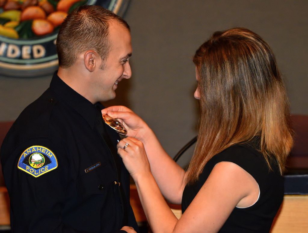 John Pasqualucci, former Orange PD, has his new Anaheim PD badge pinned to him by his wife Katy during a swearing in ceremony at Anaheim City Hall. Photo by Steven Georges/Behind the Badge OC