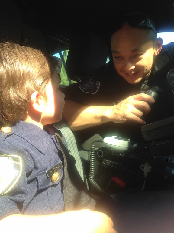 Cypress Officer Thuan Tran gives 4-year-old Justin Carlson a tour of his police car. Justin asked for a hero to come to his birthday and Officer Tran stopped by. Photo courtesy Barbara Carlson. 