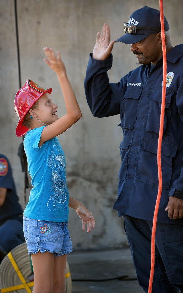Firefighter Paramedic James McDuffie of Anaheim Fire & Rescue gets a high-five from 9-year-old Keylei Wynn of Anaheim after pulling up a 50 pound firehose during Fire Service Day at the North Net Training Center in Anaheim. Photo by Steven Georges/Behind the Badge OC