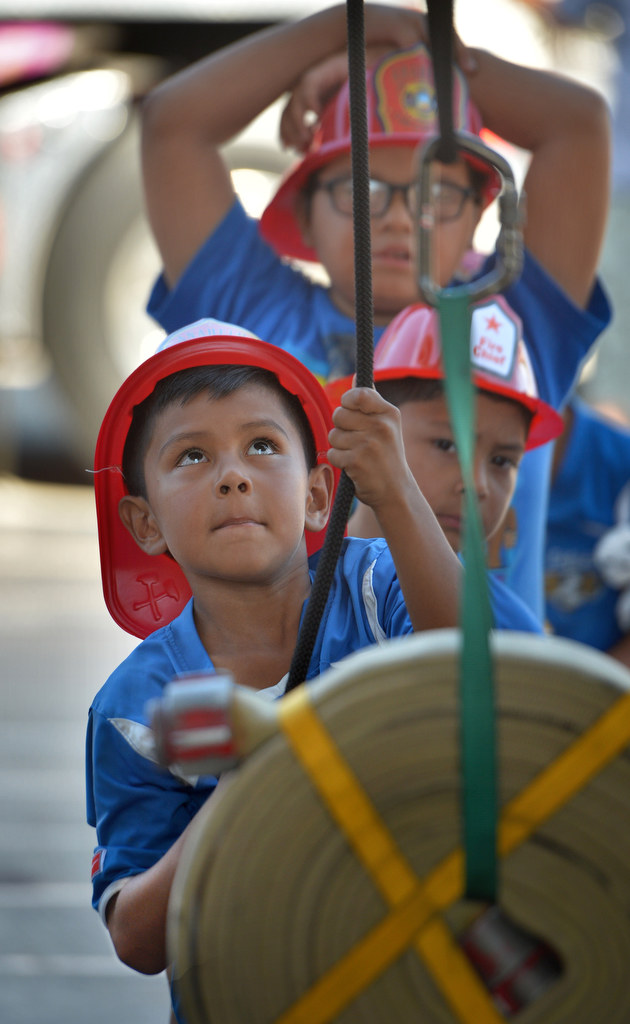 Six-year-old Olaf Ortiez of Anaheim uses pulleys to lift a 50 pound firehose during Fire Service Day at the North Net Training Center in Anaheim. Photo by Steven Georges/Behind the Badge OC