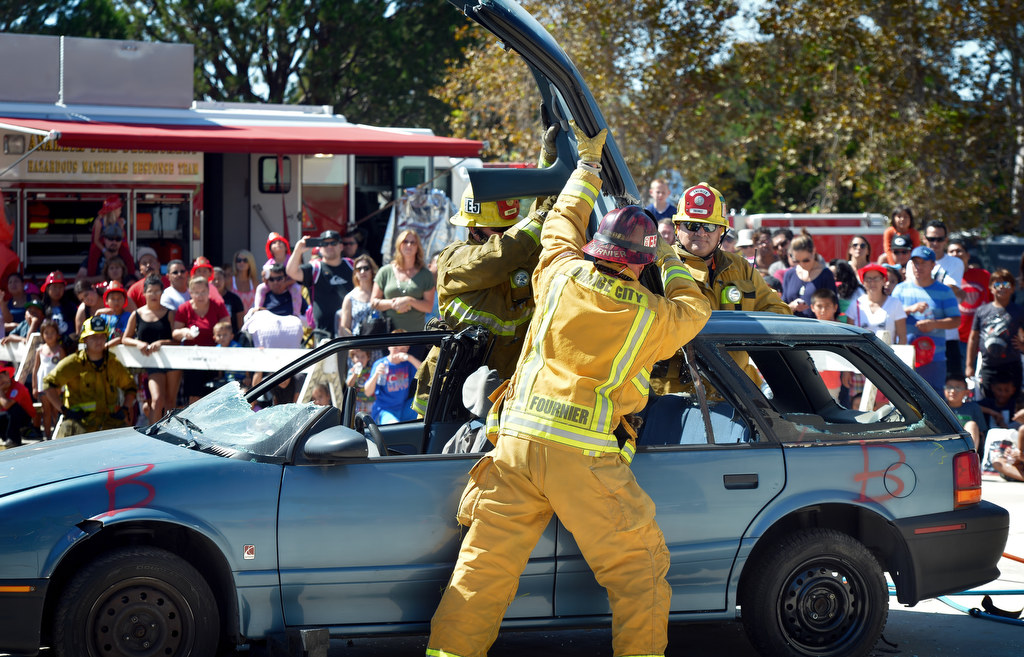 Rescue crews from the City of Orange Fire Department demonstrate how to get to a victim trapped inside a crashed car by cutting open a Saturn using the Jaws of Life during Fire Service Day at the North Net Training Center in Anaheim. Photo by Steven Georges/Behind the Badge OC
