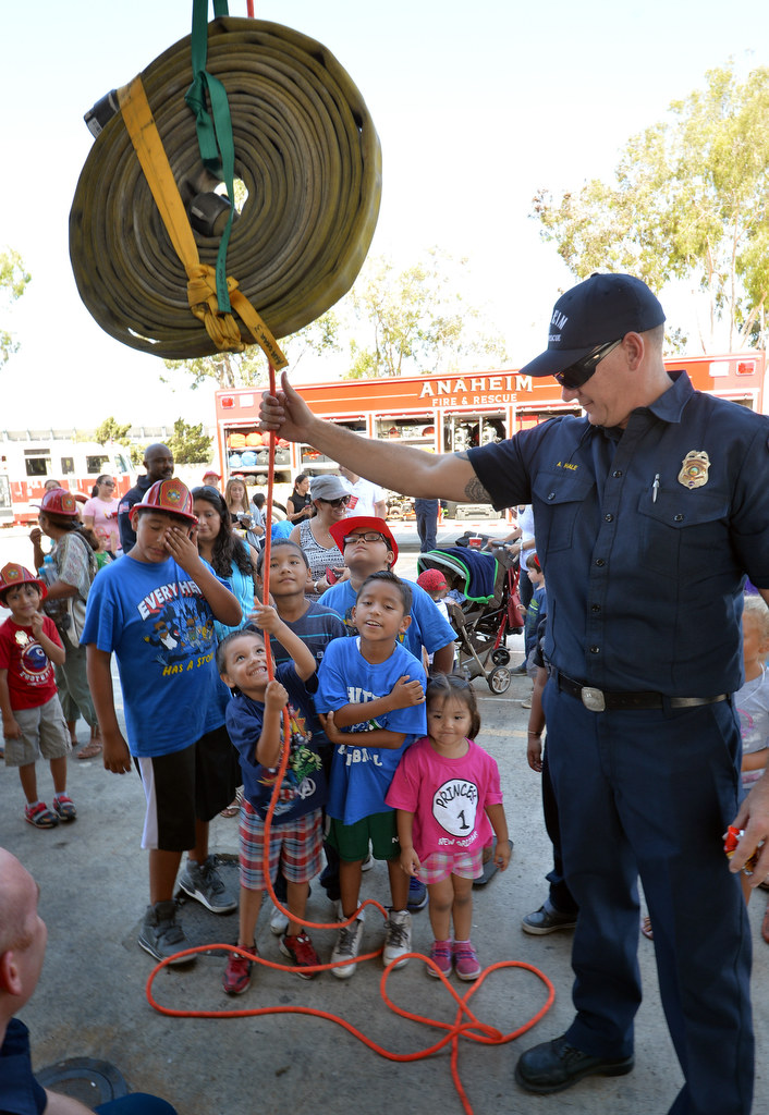 Four-year-old Jadon Orao pulls up a 50 pound firehose, with the help of pulleys and Engineer Paramedic Alex Hale of Anaheim Fire & Rescue, during Fire Service Day at the North Net Training Center in Anaheim. Photo by Steven Georges/Behind the Badge OC
