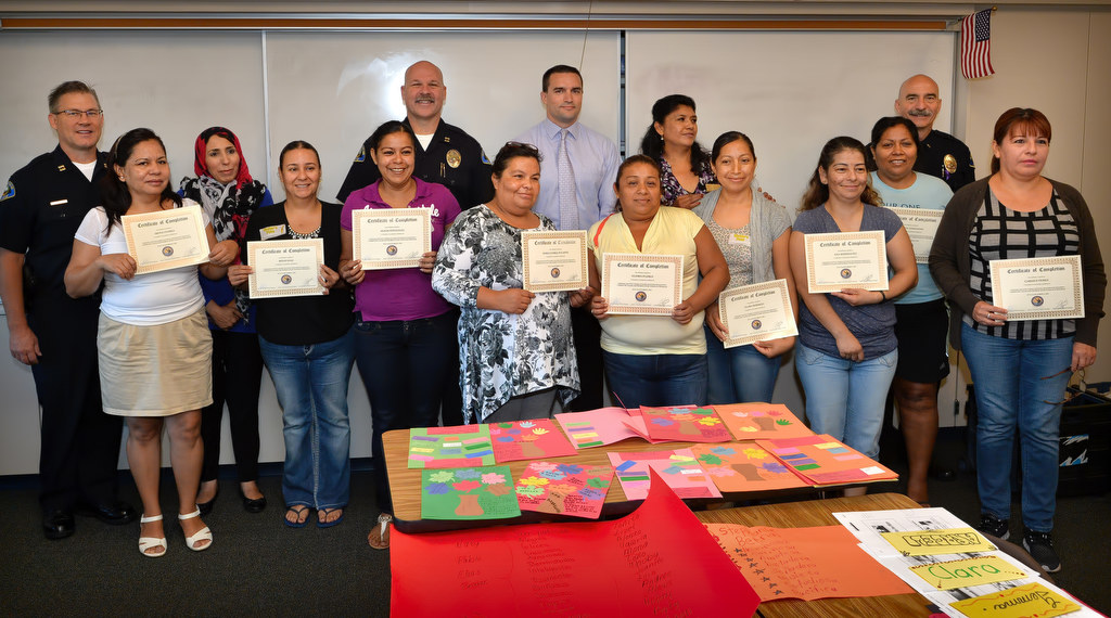 Women holding their completions certificates from the Orange County Family Justice Center Foundation for completing the Padres de Valor and Women Over Violence Program during a graduation ceremony, are from left, Irene Flores, Rosio Diaz, Alicia Gonzalez, Maria Isabel Palafox, Gloria Flores, Clara Bermejo, Ana Rodriguez, Gloria Anguiano and Carmen Perez. Supporting staff behind them are Anaheim PD Captan Eric Carter, left, Eman Aboswaeg, facilitator, Captain Steve Davis, Sgt. Brian Browne, Leticia Sanchez, facilitator and Anaheim PD Lt. James Kazakos. Photo by Steven Georges/Behind the Badge OC