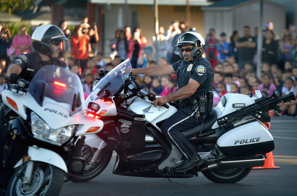Tustin Police Motorcycle Officer’s Sgt. Ryan Coe, left, and Officer Ralph Casiello help demonstrate their skills on the motorcycle during a safety assembly at Estock Elementary School in Tustin. Photo by Steven Georges/Behind the Badge OC
