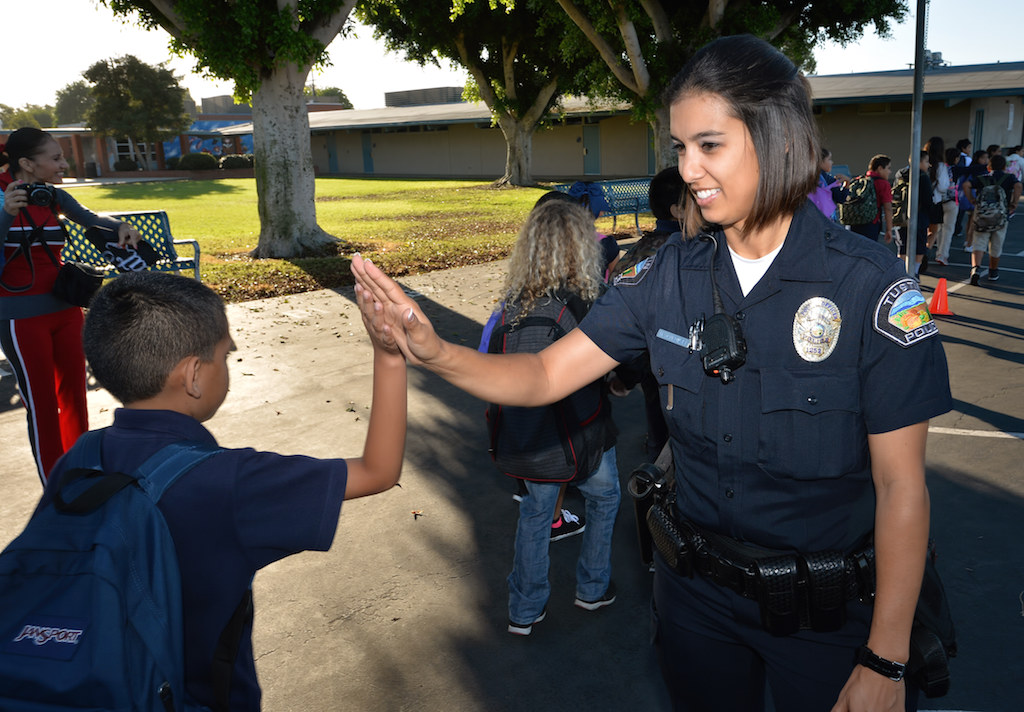 Officer Michelle Jankowski of the Tustin PD gets high-fives from students at the conclusion of a safety assembly at Estock Elementary School in Tustin. Photo by Steven Georges/Behind the Badge OC