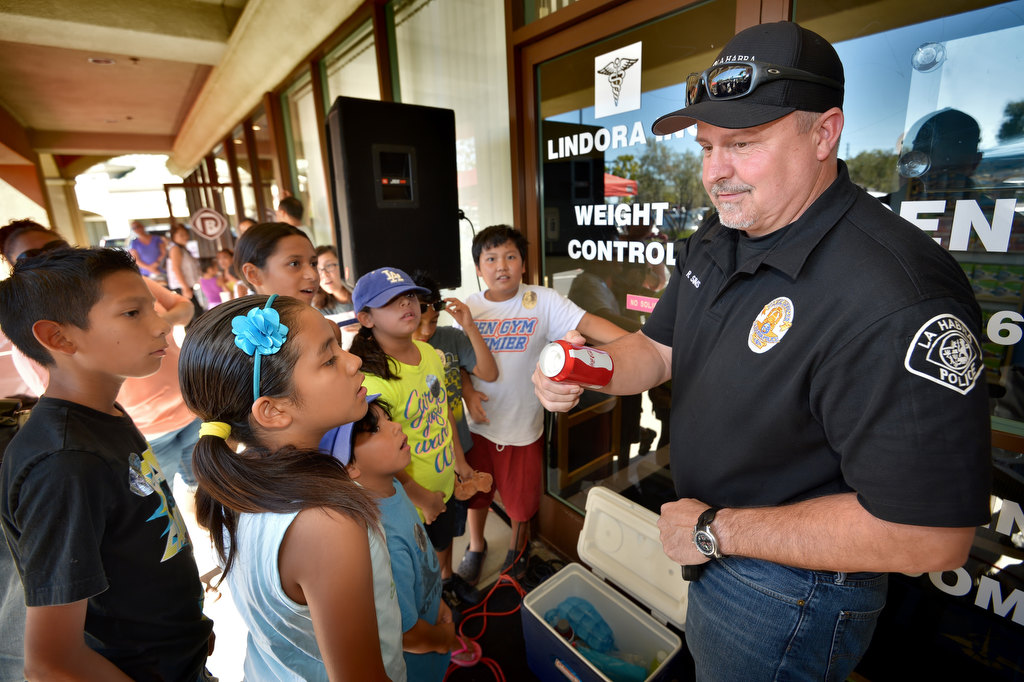 La Habra PD Officer Rob Sims shows kids the fake soda can with drugs hidden inside that Bobby, La Habra PD’s drug-sniffing dog, was able to find during a drug search demonstration, even through the can was also hidden inside a closed ice cooler. The demo was part of La Habra PD’s Pizza with a Police Pup event at Pizza Rev in La Habra. Photo by Steven Georges/Behind the Badge OC