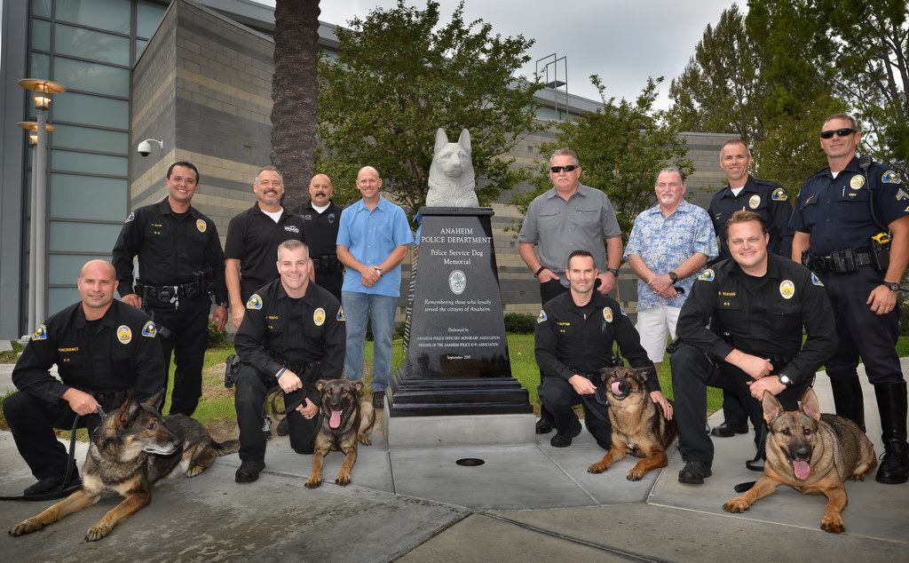 Anaheim PD’s K-9 officers ian Bonczkiewicz with his dog xxx, left, RY Young with his dog Yukon, Matt Sutter with his dog Jager, and Brett Klevos with his dog Guenther, with former and retired K-9 officers behind them during Anaheim PD’s K-9 memorial dedication at the PD’s East Sub Station. Photo by Steven Georges/Behind the Badge OC