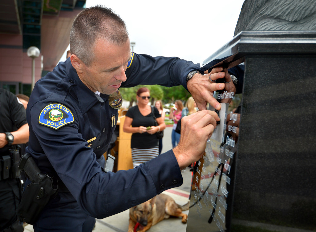 Anaheim PD Officer Brian Leist sketches the name of former police dog “Chico” after a dedication ceremony for the new police K-9 memorial at Anaheim PD’s East Sub Station. Photo by Steven Georges/Behind the Badge OC