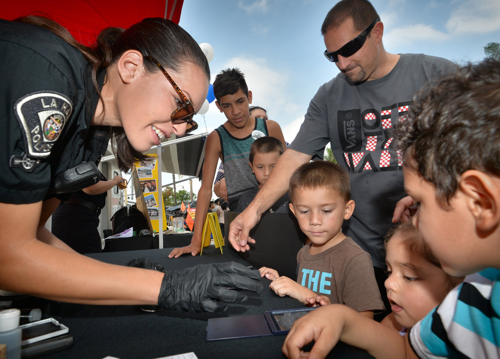 Alex Castillo, community service officer with the La Habra PD, demonstrates how to get fingerprints from a mirror the kids just touched during La Habra PDÕs open house. Photo by Steven Georges/Behind the Badge OC