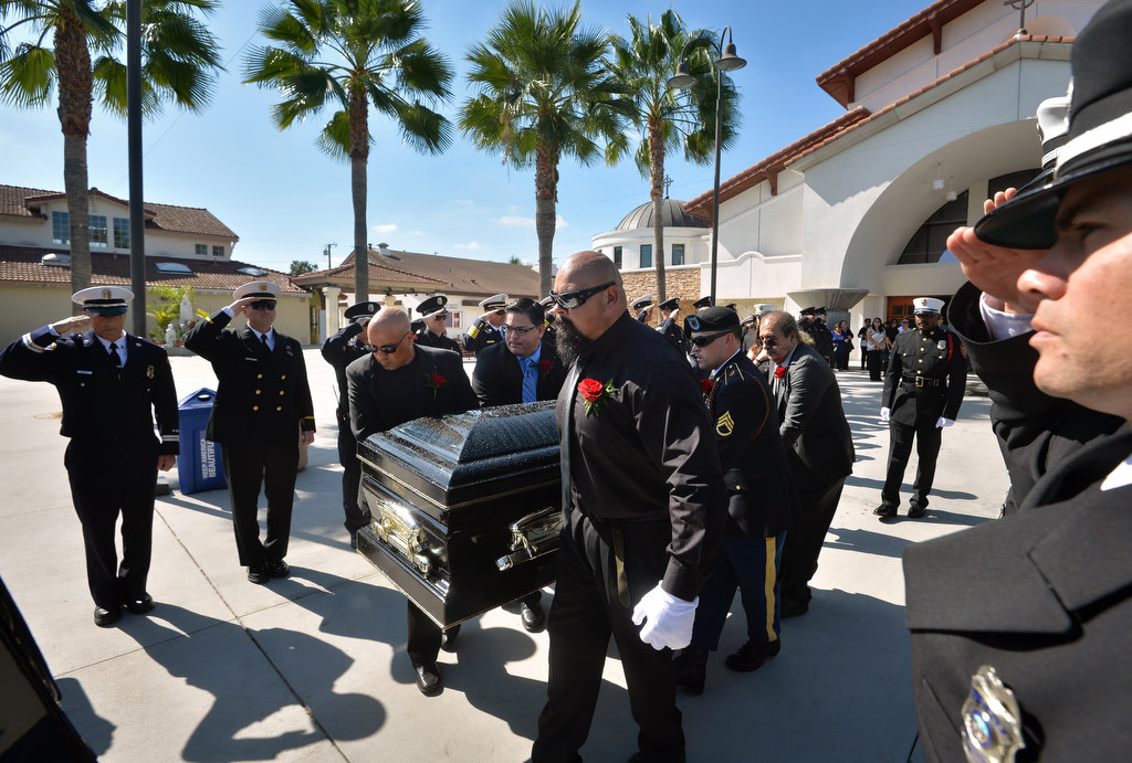 Pallbearers carry out the casket containing Metro Net Dispatcher John Delgado as firefighters salute at the conclusion of memorial services at La Purisima Catholic Church in Orange. Photo by Steven Georges/Behind the Badge OC