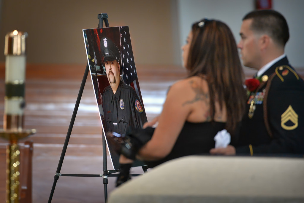 Family members pass by a portrait of Metro Net Dispatcher John Delgado during memorial services inside La Purisima Catholic Church in Orange. Photo by Steven Georges/Behind the Badge OC