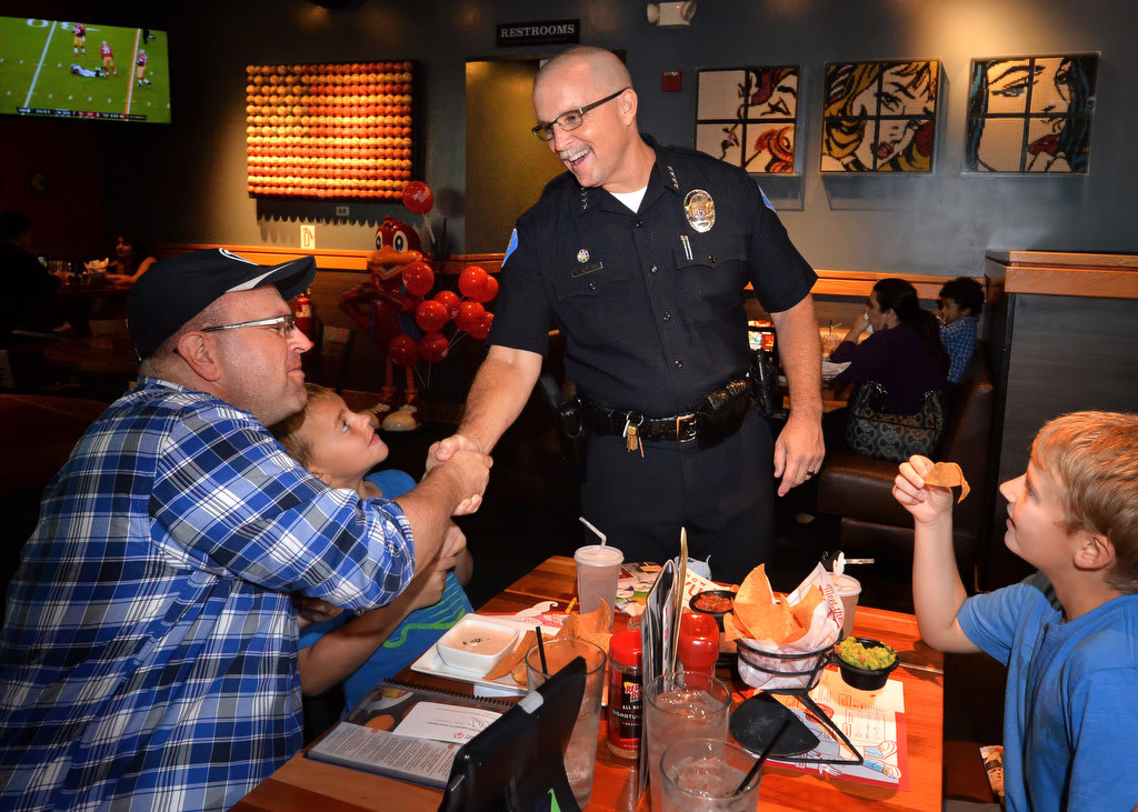 Garden Grove Police Chief Todd Elgin shakes hands with Aaron Hardy of Heber City Utah and his 8-year-old son Luke Hardy, next to him, as the chief visits tables at Red Robin Restaurant in Garden Grove during the Tip a Cop fundraiser for Special Olympics. Photo by Steven Georges/Behind the Badge OC