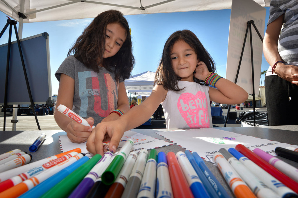Itza Perez of Fullerton, left, and her sister Renata Perez write letters to Fullerton Police and Fire that reads “Thank you for taking ker of us” and includes pictures of a policeman helping a little girl and a firefighter putting out a fire, at the Team Kids Challenge booth, part of Fullerton PD’s Fourth Annual Police Department Open House. Photo by Steven Georges/Behind the Badge OC