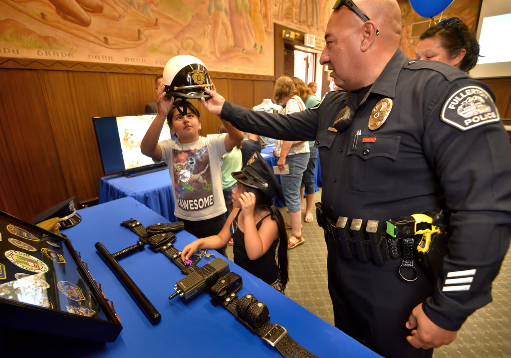 Fullerton PD Officer Miguel Siliceo helps Eli Garcia, 11, of Buena Park, and his sister Sofie Garcia, 5, try on police motorcycle helmets and hats during Fullerton PD’s Fourth Annual Police Department Open House. Photo by Steven Georges/Behind the Badge OC