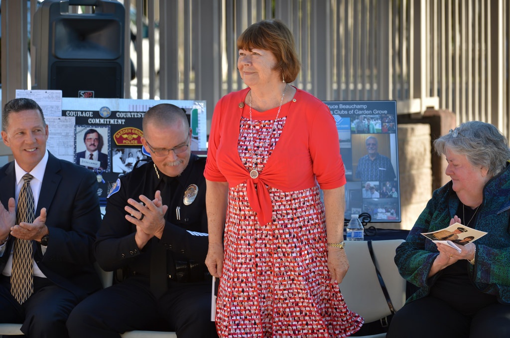 Lollie Beauchamp, widow of GGPD Sgt. Bruce Beauchamp, stands before her speech as she is applauded by former GGPD Chief Kevin Raney, left, Chief Todd Elgin and Pat Halberstadt of the Boys & Girls Clubs of Garden Grove, during a naming ceremony for the Bruce Beauchamp Juvenile Justice Center. Photo by Steven Georges/Behind the Badge OC