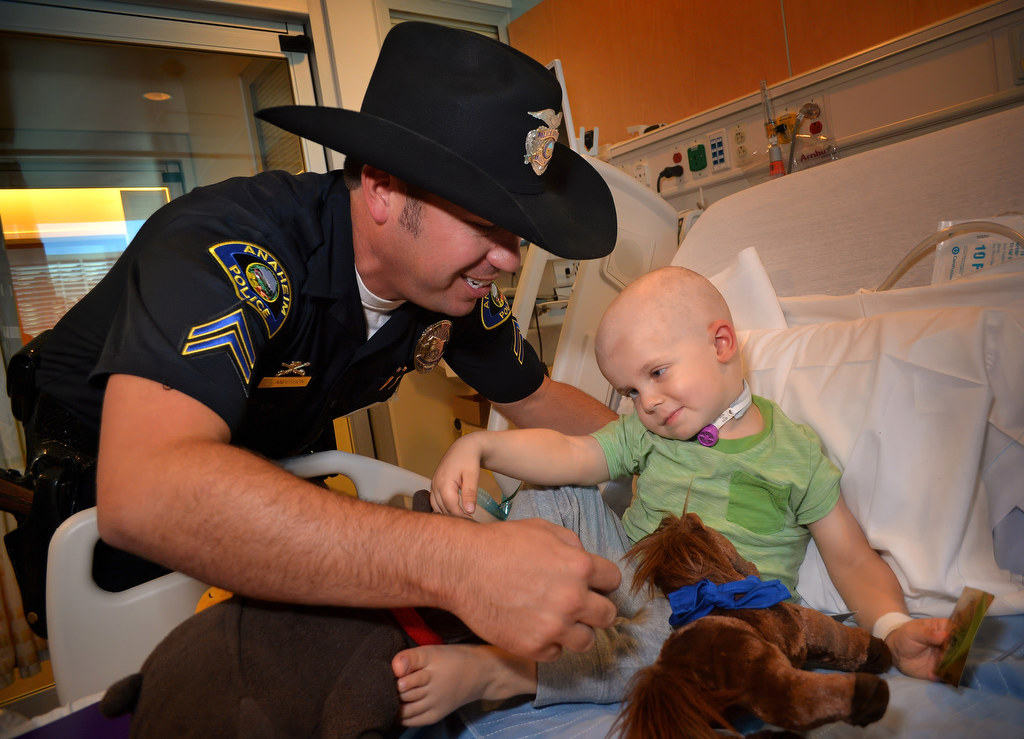 Anaheim PD Officer Eric Anderson gets a hug from 3-year-old Amos Ross of Cambridge, England, as the APDÕs mounted division payed a visit to the kids at CHOC Hospital. Amos, who is being treated for cancer, was on vacation with his parents when he had an unscheduled need for hospitalization. Photo by Steven Georges/Behind the Badge OC