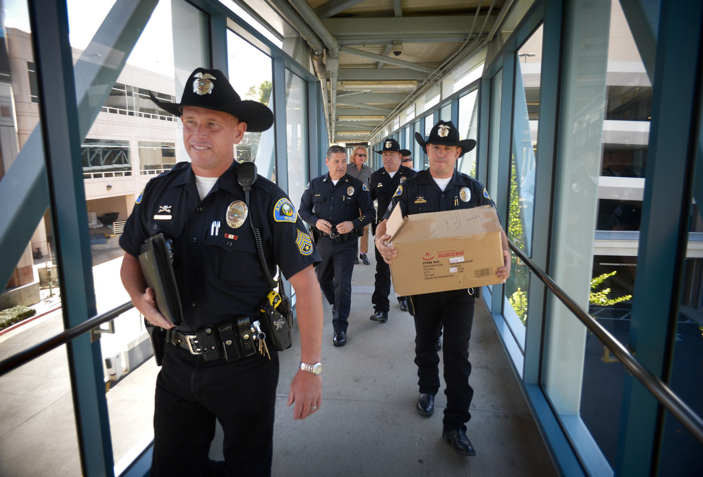 Sgt. Rodney Duckwitz of the Anaheim Police Mounted Unit, left, walks across the bridge to the CHOC hospital as Officer Eric Anderson caries a box full of stuffed toy horses for kids staying at the hospital. Photo by Steven Georges/Behind the Badge OC