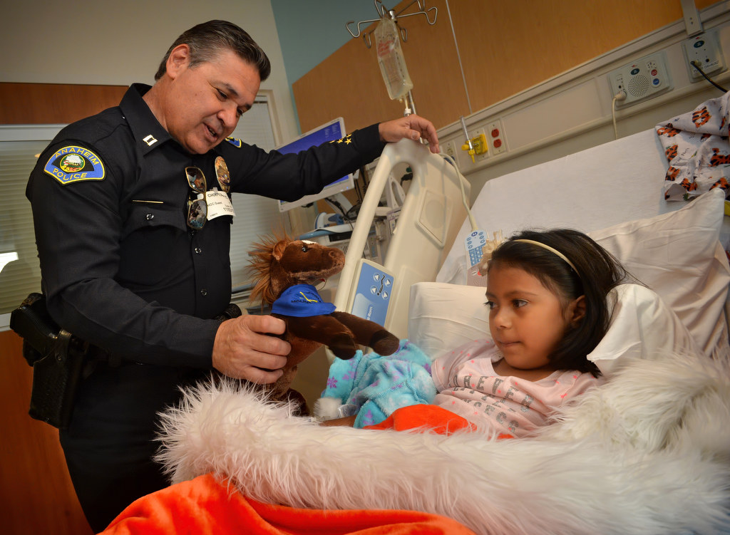 Anaheim PD Captain Ben Hittesdorf presents 6-year-old Arinna Sanchez with a toy horse during a visit to CHOC Hospital. Photo by Steven Georges/Behind the Badge OC