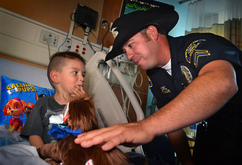 Anaheim Police Officer Eric Anderson gives 4-year-old Justin Gonzalez of Costa Mesa a toy horse during a visit to CHOC Hospital. The horses are from the Anaheim Police Mounted Unit. Photo by Steven Georges/Behind the Badge OC