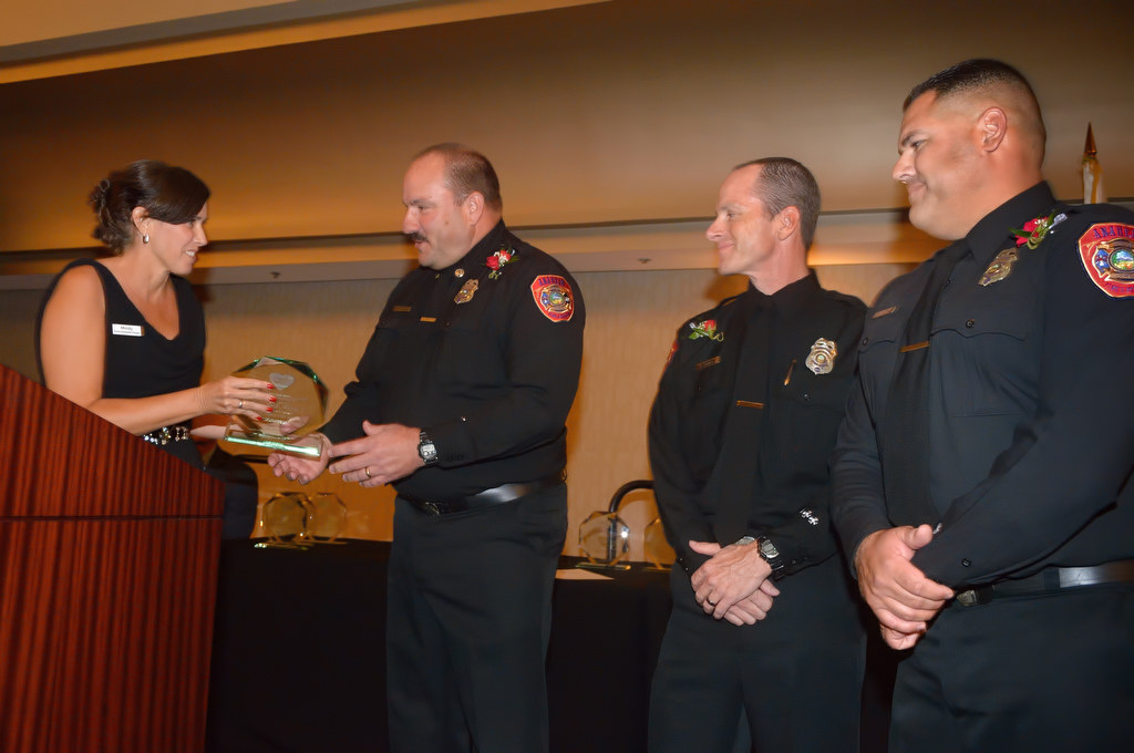 TIP Manager Mindy Daffron presents Anaheim Fire & Rescue recipients Captain Andy Ball, left, Engineer Roger Domen and Firefighter Jeremy Keith with the Heroes with Heart award during an awards dinner at the Hilton Anaheim. Firefighter Denny Munson was not present. Photo by Steven Georges/Behind the Badge OC