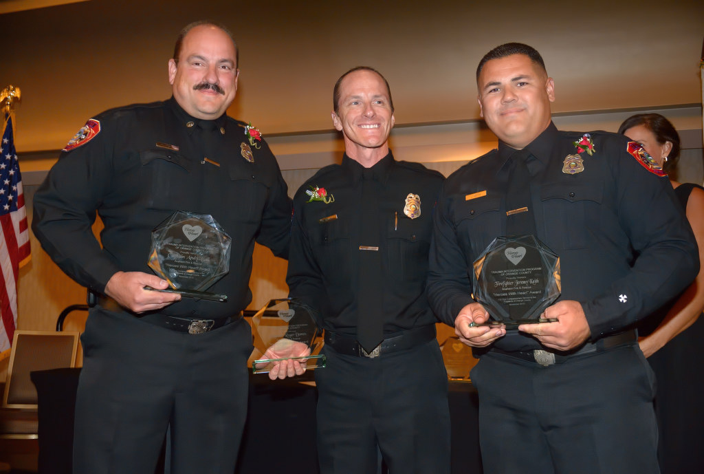 Anaheim Fire & Rescue recipients of the Heroes with Heart award Captain Andy Ball, left, Engineer Roger Domen and Firefighter Jeremy Keith receive the recognition on stage during an awards dinner at the Hilton Anaheim. Firefighter Denny Munson was not present. Photo by Steven Georges/Behind the Badge OC