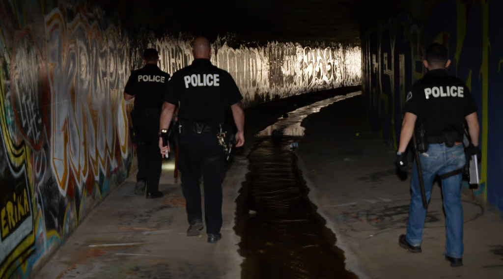 Officers from Fullerton PD and La Habra PD walk through flood control tunnels covered in graffiti near Harbor Blvd. and Imperial Hwy. looking for homeless people that might be living there, which would be dangerous should it rain. Photo by Steven Georges/Behind the Badge OC
