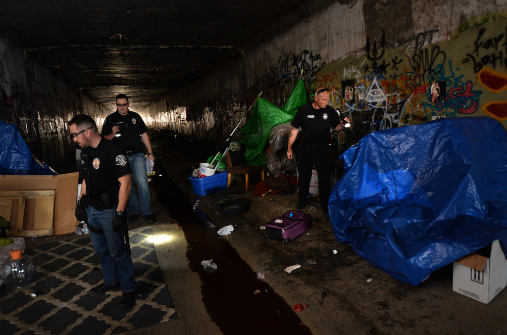 La Habra PD Officer Nate Garcia, left, La Habra PD Officer Muris Lucarevic and Fullerton PD Cpl. Dan Heying inspect a sleeping area inside of the dark and wet flood control tunnels near Beach Blvd. and Imperial Hwy. People living there would be in danger in the event of rain. Photo by Steven Georges/Behind the Badge OC
