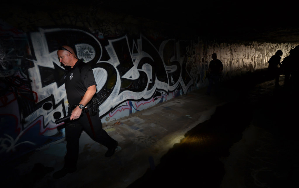 Fullerton PD Cpl. Dan Heying walks through a dark flood control tunnel looking for homeless people that might be living in there. Photo by Steven Georges/Behind the Badge OC