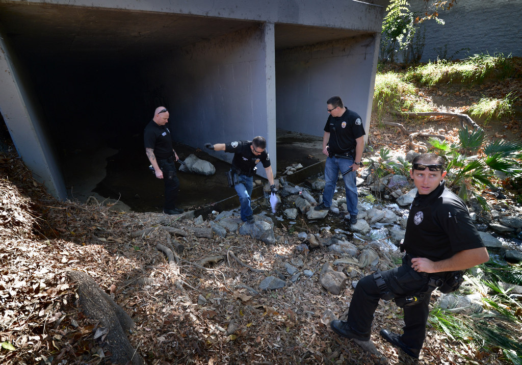Fullerton PD Cpl. Dan Heying, left, La Habra PD Officer Nate Garcia, La Habra PD Officer Muris Lucarevic and Fullerton PD Officer Brad Fernandes walk through the hazardous and wet flood control tunnels looking for homeless people living in them. Photo by Steven Georges/Behind the Badge OC