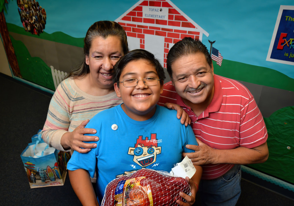 GRIP student from Topaz Elementary in Fullerton Juan Ugalde, 11, holds the turkey he received from the GRIP program while standing next to his parents, Silvia and Simon at the school. Photo by Steven Georges/Behind the Badge OC