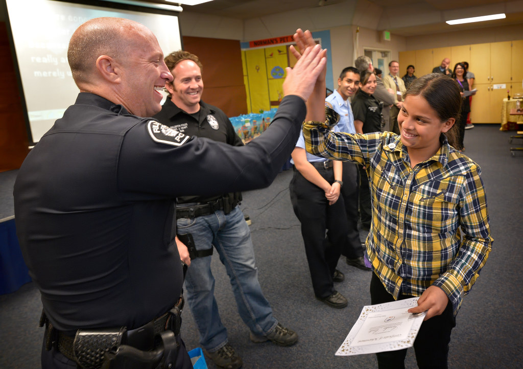 Sarahi Brito gets a high-five from Fullerton Police Chief Dan Hughes as she receives her outstanding achievement certificate from OC GRIP and Topaz Elementary School, and a free Turkey with traditional fixings for her family during a gathering at the school. Photo by Steven Georges/Behind the Badge OC