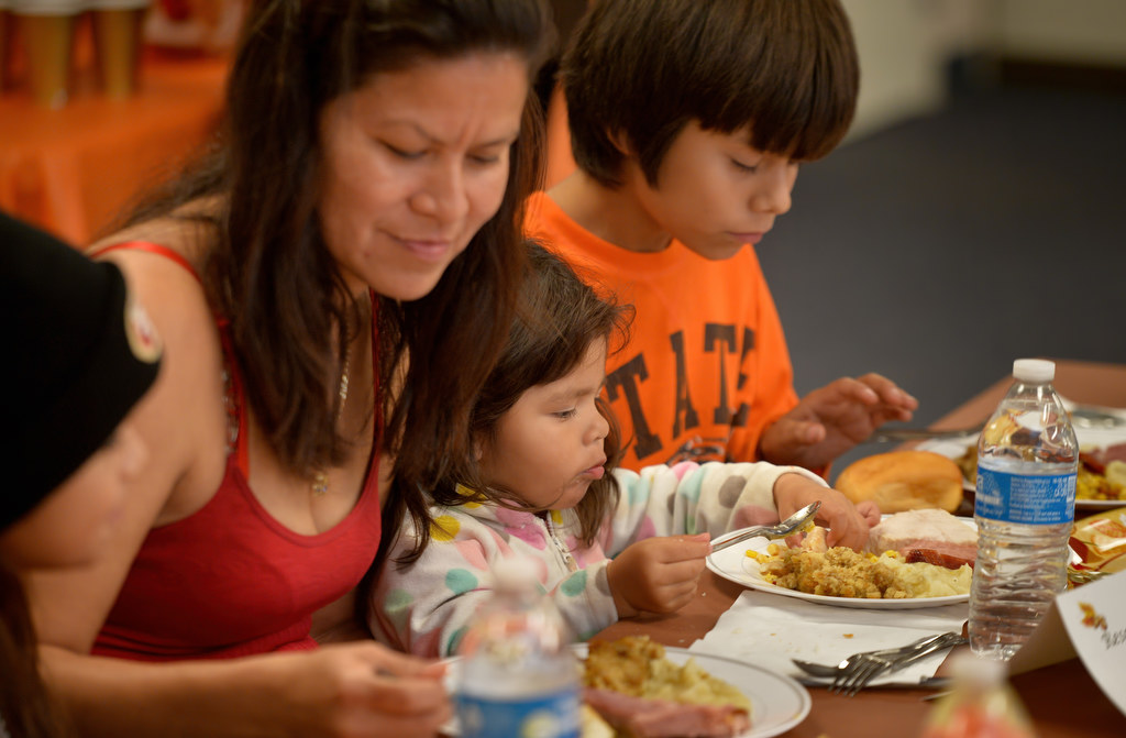 Araceli Rodriguez eats a turkey dinner with her three kids, GRIP student Eddie Zarate, 11, right, Adonait Hernandez, 2, and Joemy Zarate, 9, far left, during a GRIP gathering at Topaz Elementary School. Photo by Steven Georges/Behind the Badge OC