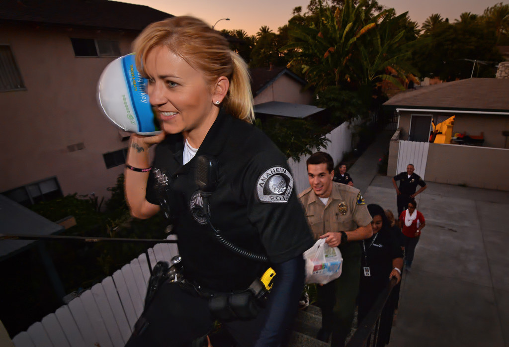 Anaheim PD Officer Merisa Leatherman, left, caries a turkey up to a GRIP recipient’s home with Anaheim Police Cadet Jake Seiders carrying the rest of the Thanksgiving meal up behind her as they deliver turkey meals to students. Photo by Steven Georges/Behind the Badge OC