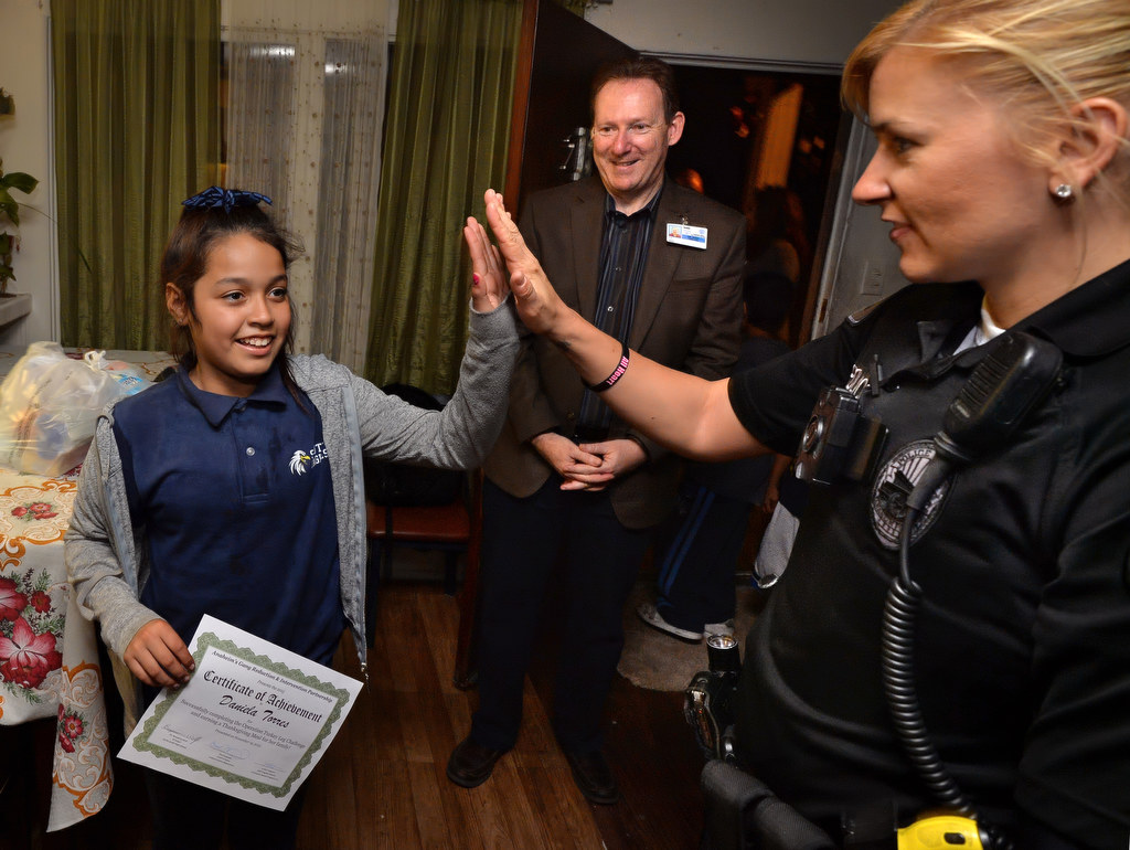 Daniela Torres, 12, gets a high-five from Anaheim PD Officer Merisa Leatherman after receiving a Thanksgiving meal for her family through the GRIP program. Photo by Steven Georges/Behind the Badge OC