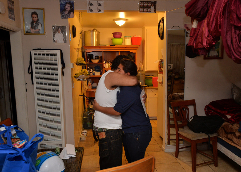 Jasmin Miranda, 13, gets a hug from her brother after Jasmin had a Thanksgiving meal delivered to her family that she earned from the GRIP program. Photo by Steven Georges/Behind the Badge OC