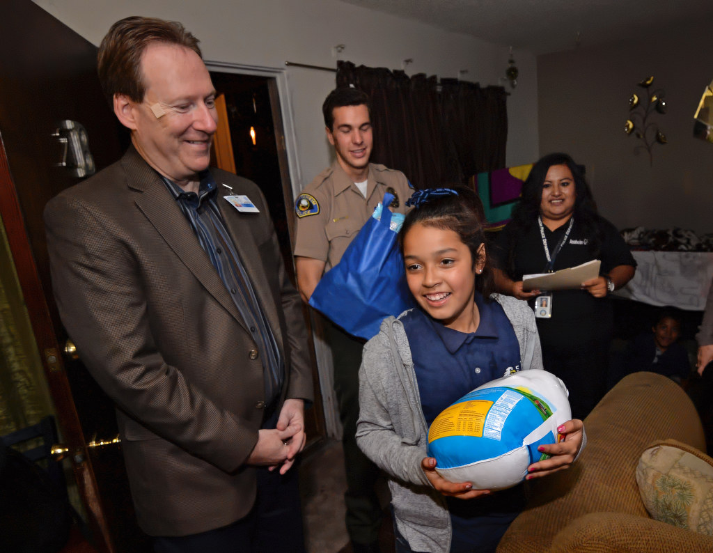 Daniela Torres, 12, holds the Thanksgiving turkey delivered for her family from a group that included Dr. Benjamin Wolf, principal for South Junior High, left, Anaheim Police Cadet Jake Seiders and Carmela Mendoza, case manager for Anaheim PD’s GRIP program. Photo by Steven Georges/Behind the Badge OC