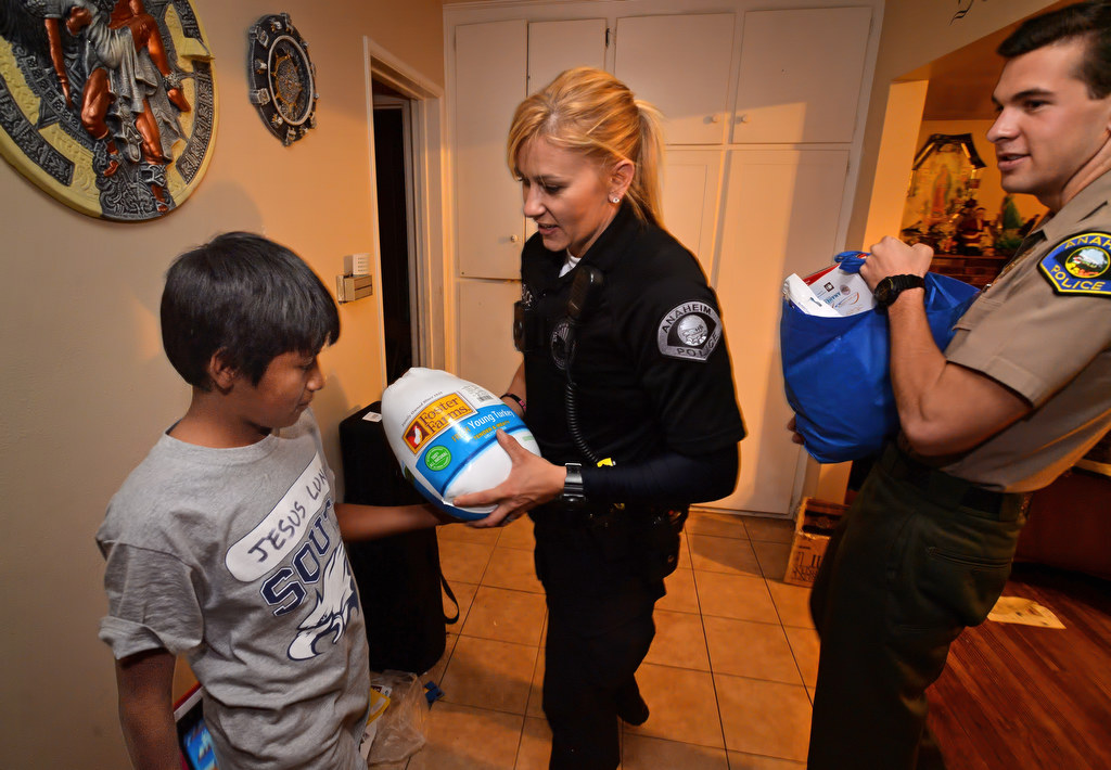 Jesus Luna, 12, receives a turkey from Anaheim PD Officer Merisa Leatherman and the rest of the Thanksgiving meal from Cadet Jake Seiders, right, that Jesus earned for his family from the GRIP program. Photo by Steven Georges/Behind the Badge OC