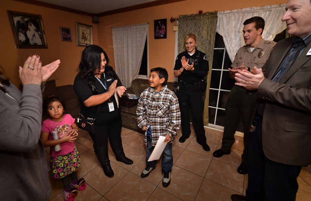 Daniel Reyes Gonzalez, 10, receives applause from the group who delivered the Turkey dinner he received from the GRIP program that includes Carmela Mendoza, case manager for Anaheim PD’s GRIP, left, Officer Merisa Leatherman, Cadet Jake Seiders and Dr. Benjamin Wolf, principal for South Junior High. Photo by Steven Georges/Behind the Badge OC