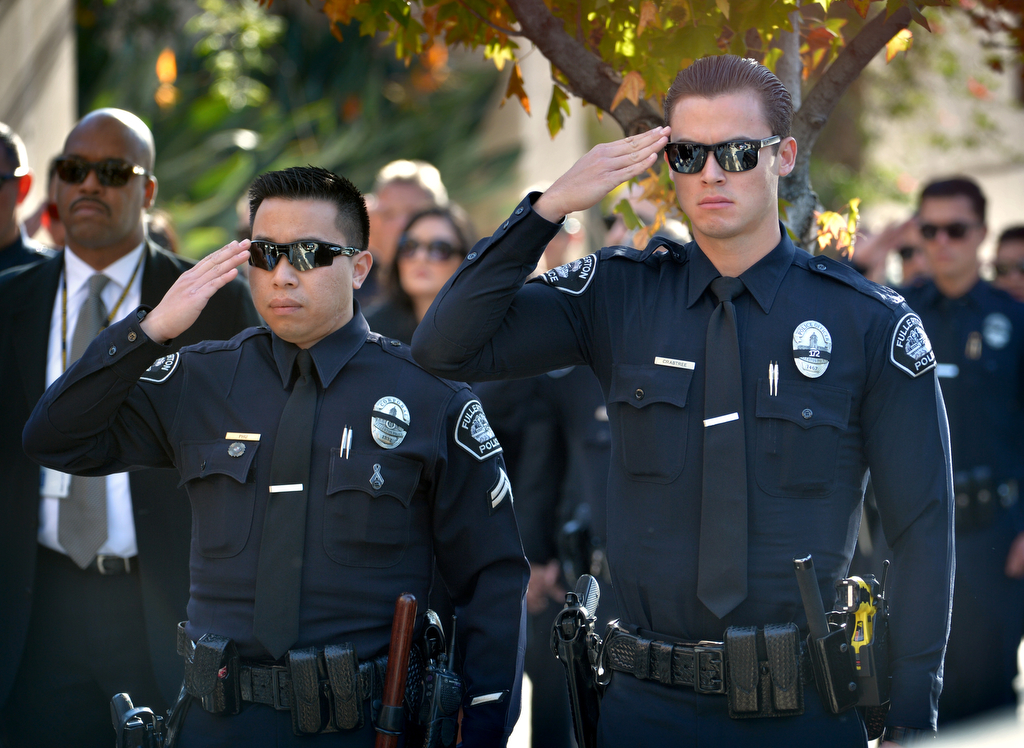 Fullerton PD’s Cpl. Billy Phu, left, and Officer Davis Crabtree salute as the casket of Downey PD Officer Ricardo "Ricky" Galvez is carried into the Cathedral of Our Lady of the Angels during a funeral service. Photo by Steven Georges/Behind the Badge OC