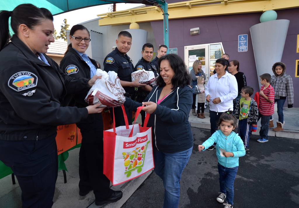 Imelda Andrea of Tustin and her granddaughter, 3-year-old Lia Gonzalez, receive a free turkey from the Tustin PD the day before Thanksgiving at the Tustin Family & Youth Center. Photo by Steven Georges/Behind the Badge OC