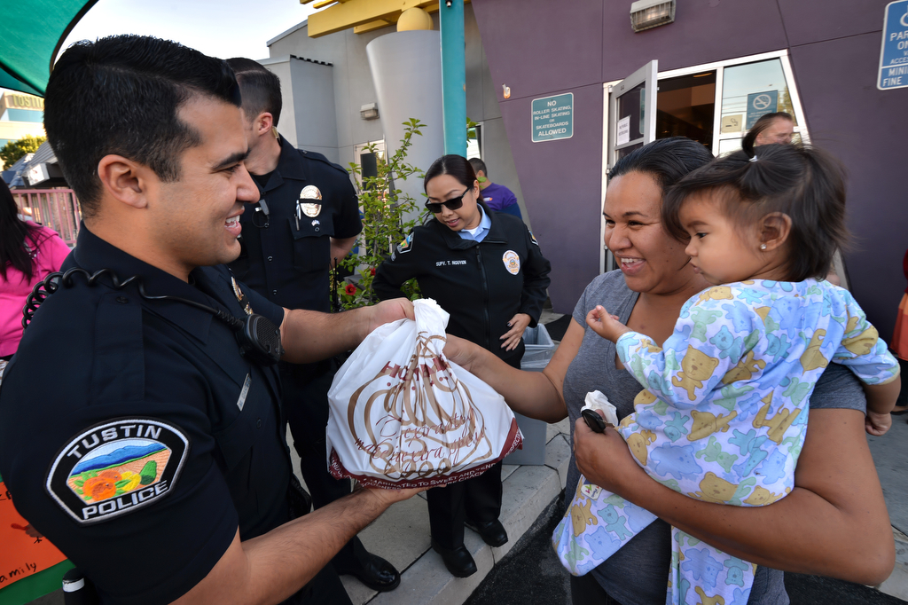 Tustin PD Officer Michael Carter hands a free turkey to Jessica Moreno of Tustin and her daughter Kaylee Mota, 16 months, the day before Thanksgiving at the Tustin Family & Youth Center. Photo by Steven Georges/Behind the Badge OC