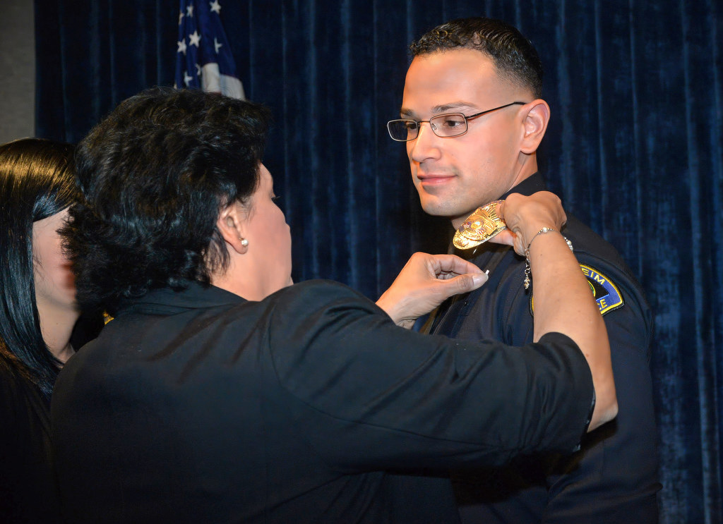 Anaheim PD’s new officer, Ruben Guzman, has his new badge pinned to him by his mother, Jenny Guzman, during a promotion ceremony. Photo by Steven Georges/Behind the Badge OC