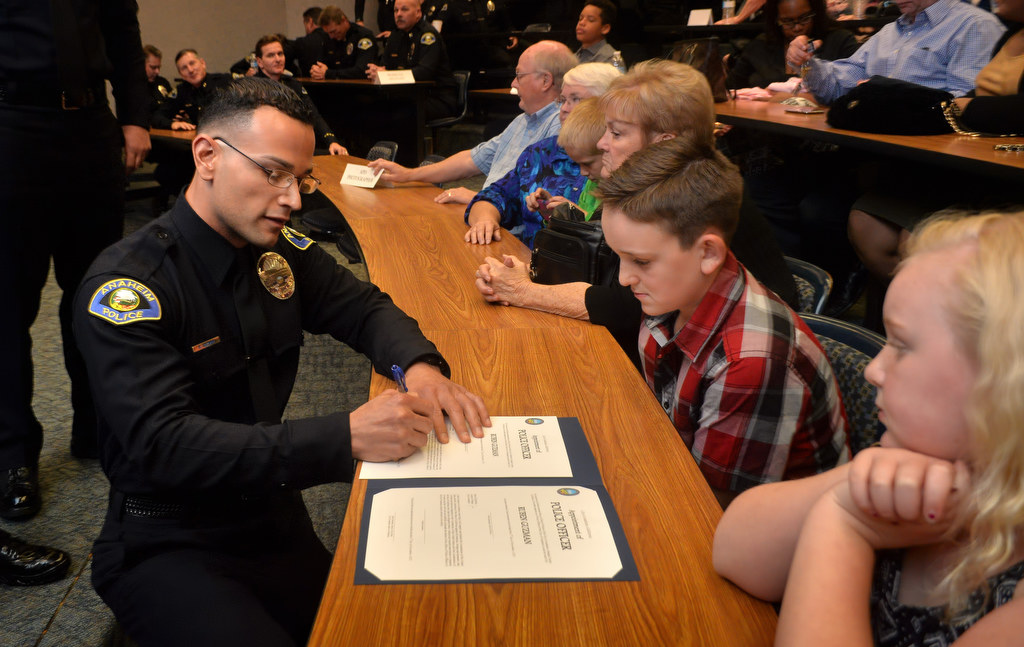 Ruben Guzman, kneels as he signs the official papers making him one of Anaheim’s newest police officer at the conclusion of a ceremony at the Anaheim PD. Photo by Steven Georges/Behind the Badge OC