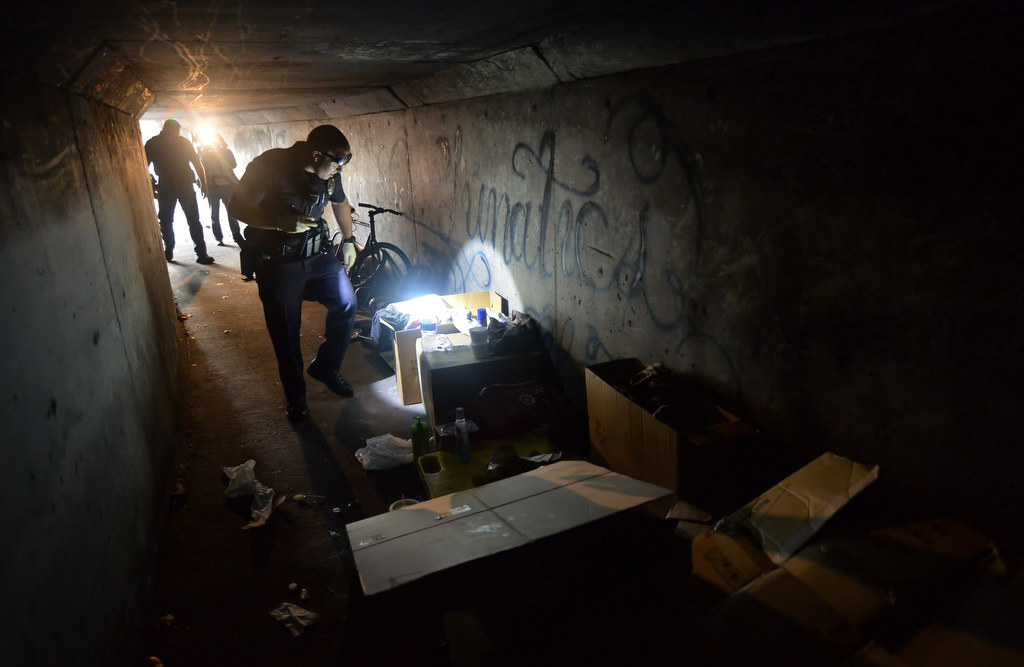A Garden Grove officer inspects the items and trash in a storm drain tunnel under Brookhurst St. where people were living. Photo by Steven Georges/Behind the Badge OC