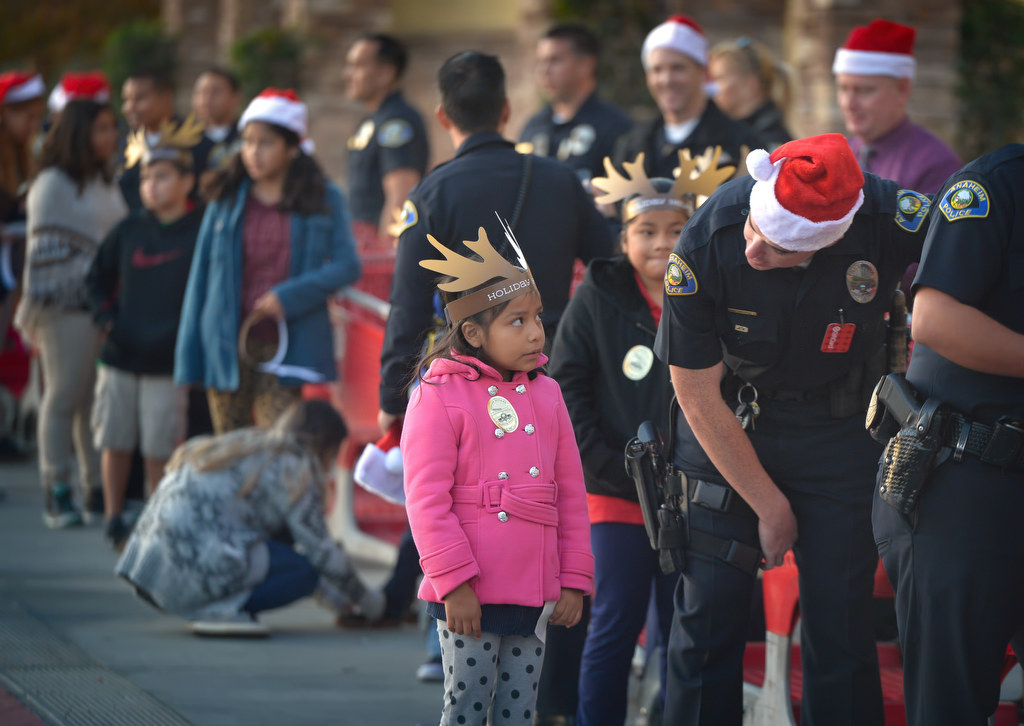 Seven-year-old Suzette Pablo waits in line with Anaheim PD Officer Bill Segletes as they wait in line for the doors to open at a local Target store for the annual Shop With a Cop event. Photo by Steven Georges/Behind the Badge OC
