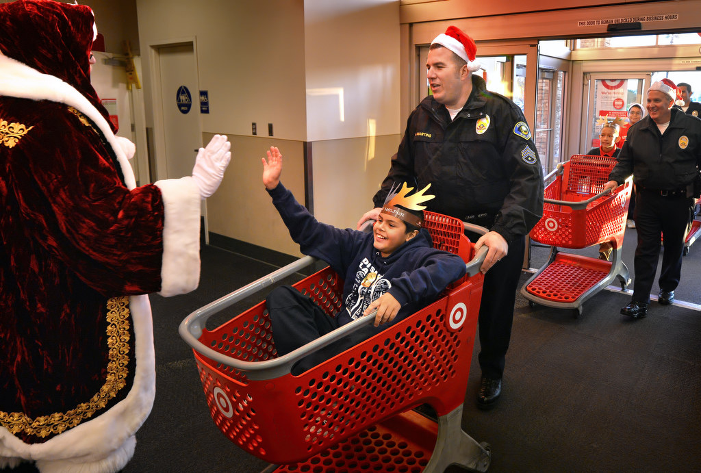 Sgt. Rafael Martins walks into the local Target store with a young boy as he gives Santa a high-five for the start of Anaheim PDÕs Shop With a Cop. Photo by Steven Georges/Behind the Badge OC
